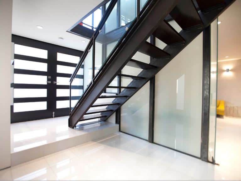 这个工业风格门厅的亮点是金属楼梯，看起来就像属于工厂一样。它有一种深色的金属色调，与主门的深色色调相匹配，磨砂玻璃板与楼梯的磨砂玻璃墙相匹配。