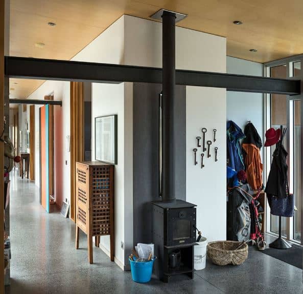 这个工业风格的门厅的温暖和欢迎的态度是由于靠近储藏室的独立黑铁壁炉，里面装满了夹克、帽子和包。这与灰色的工业风格地板搭配得很好，与墙壁的浅色形成对比。