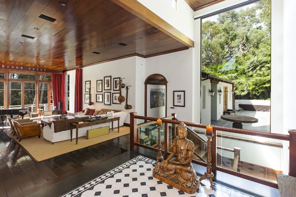 位于加州马里布(Malibu)的一座住宅曾为音乐人Kid Rock所有，这里有一间巴厘岛风格的客厅，带有热带木质氛围，深色硬木地板和木板条天花板。这个空间包括一张白色大沙发、一对棕色扶手椅、一架钢琴，整个空间都是木制工艺。大玻璃窗通向后甲板。