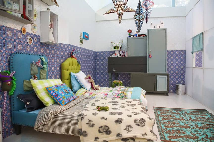 共享的儿童卧室拥有华丽的蓝色和绿色床，以及模块化的橱柜，这些橱柜被放置在可爱的碎花壁纸主导的白墙上。