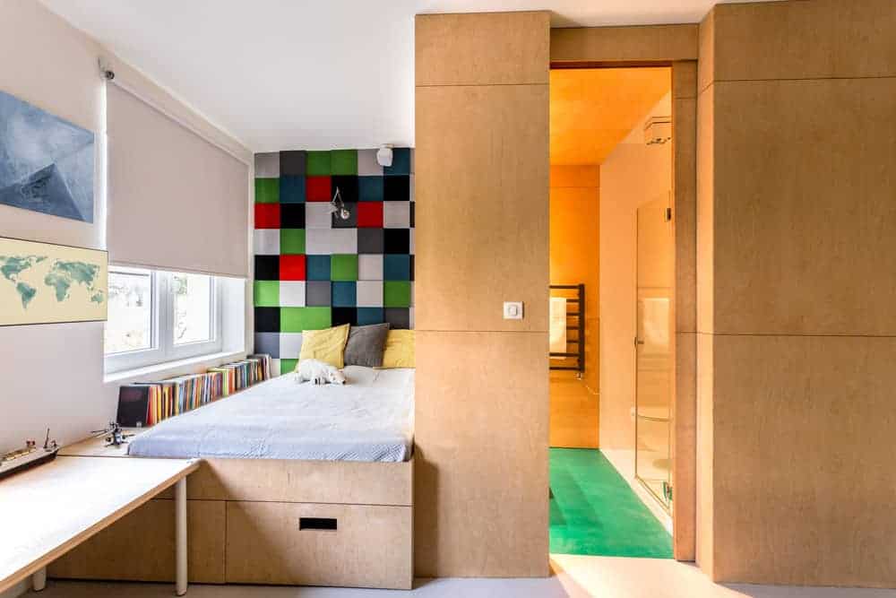 格子墙为这间儿童卧室增添了引人注目的特色，卧室里有一张嵌壁式床，与木镶板墙相匹配，还有一扇覆盖着白色卷帘的玻璃窗。