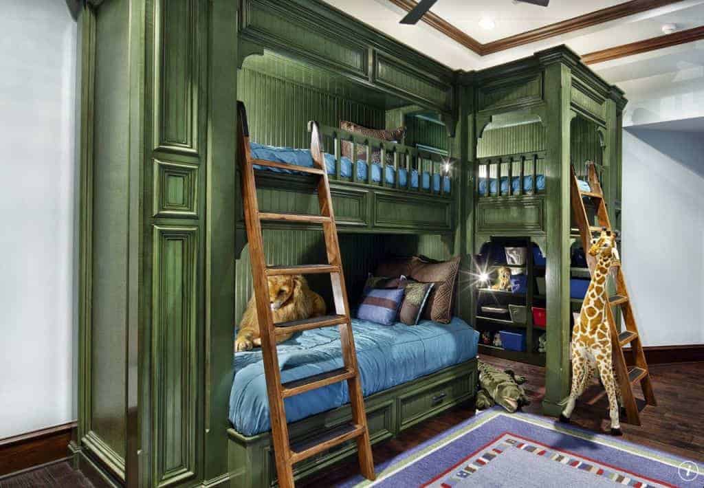 儿童卧室以丛林为主题，拥有蓝色镶边地毯和苔藓绿色床头板双层床，下面有开放式书架。