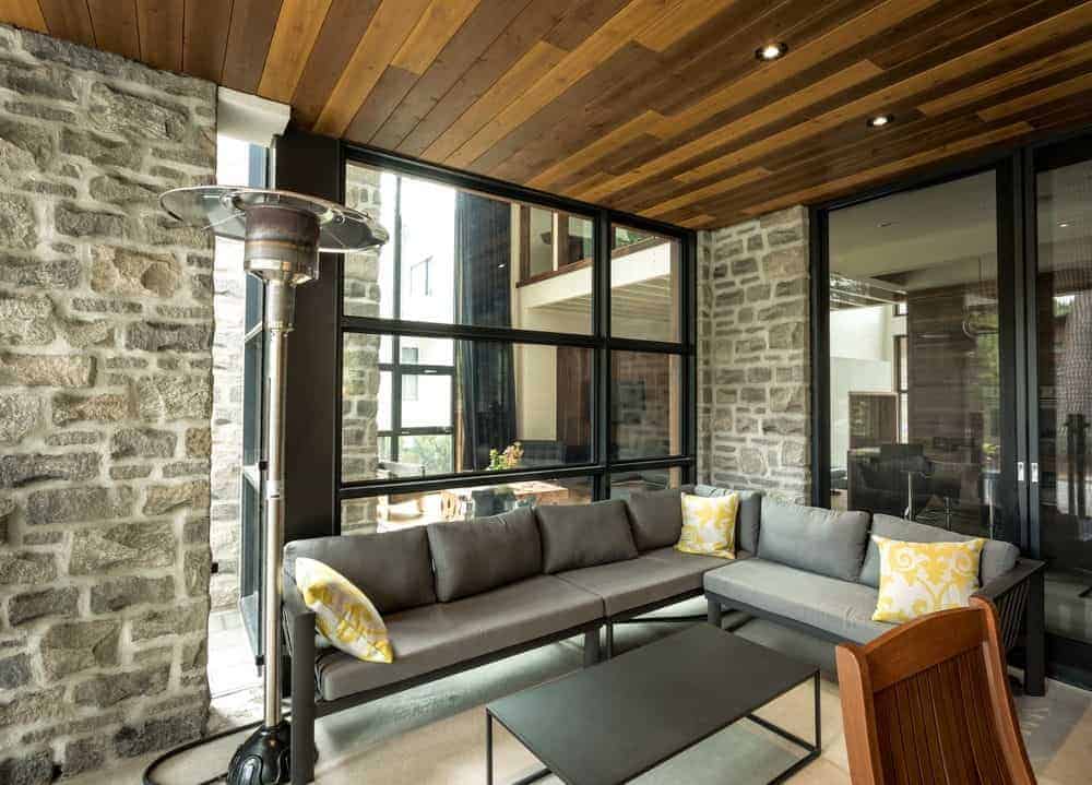 客厅设有石墙和木制天花板。窗户和门都是玻璃的，还有一张舒适的灰色沙发。