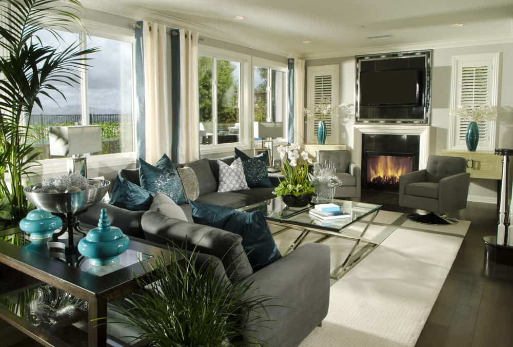 这个客厅提供时尚的灰色座椅以及多个室内绿色植物。上面还有一个壁炉和一台电视。