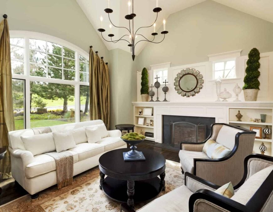 一个小的起居空间，有一个白色的沙发和一个圆形的中央桌子，还有一个壁炉，由一个华丽的枝形吊灯照亮。