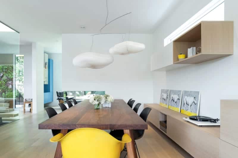木制长方形餐桌的顶部有两个独特的白色垂饰灯看起来像云。这顺利的光色调的墙壁和天花板看起来像实木地板的云漂浮在天空匹配的橱柜和货架。