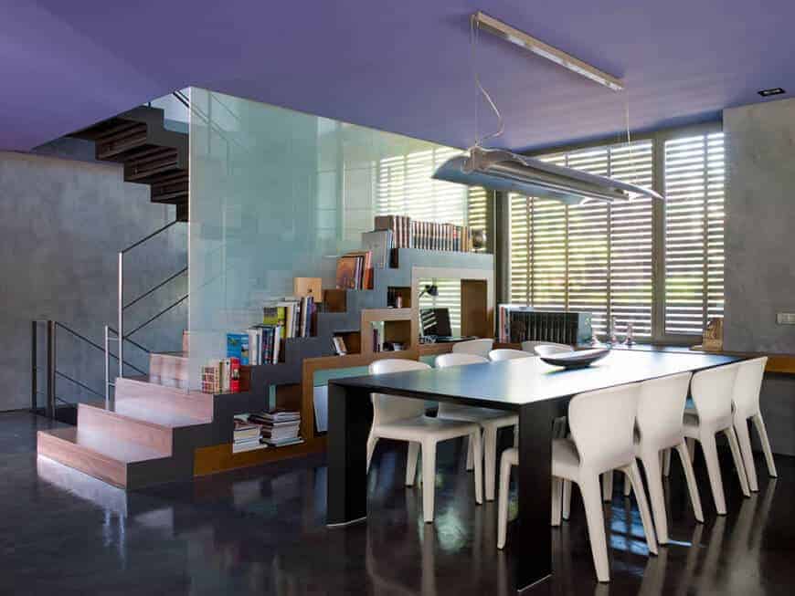 这个现代餐厅的楼梯白色现代椅子,坚决反对黑人现代餐桌和industrial-style地板相匹配的industrial-style荧光灯挂在天花板上。
