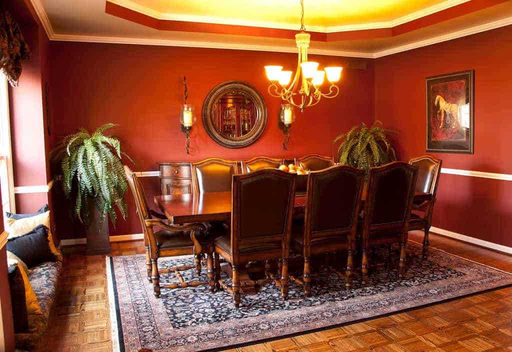 仿古风格矩形的木制餐桌搭配棕色皮革坐垫的椅子。这些都是与餐厅内阁和轮安装在墙上的镜子上面温暖的黄色灯光明亮的吊灯。