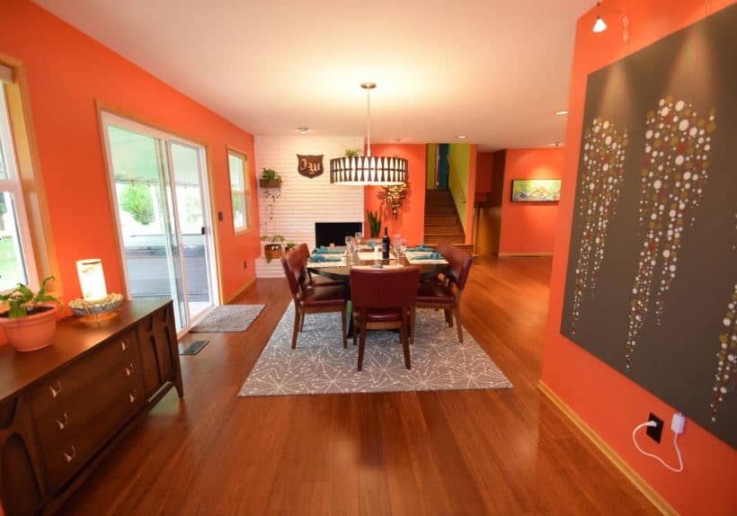 餐厅欢快的橙色墙壁是对硬木地板的极大补充，与餐厅的木质色调相匹配，灰色图案地毯和现代圆形吊灯下。