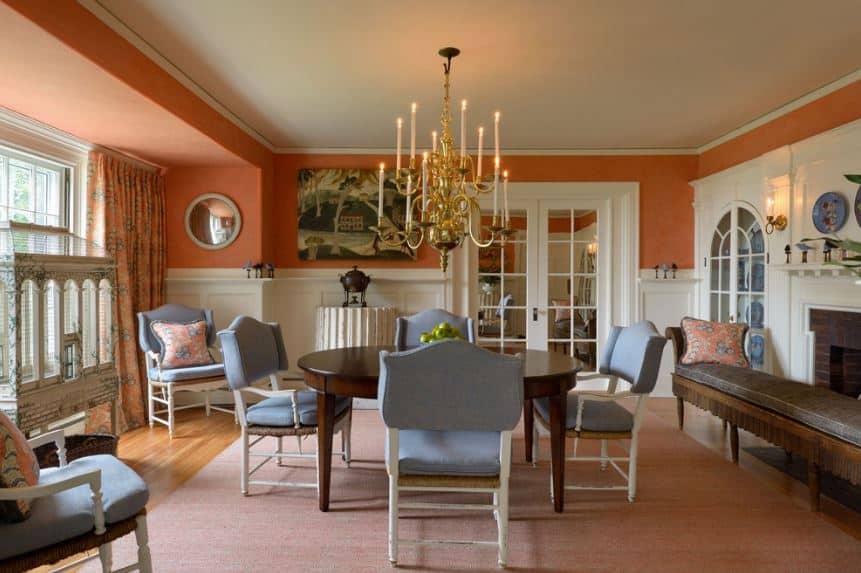 多层金色吊灯在这个房间里很显眼，浅蓝色的椅垫环绕着深色的木桌，与硬木地板上的粉红色地毯相映成趣，橙色的墙壁与之相得益彰。