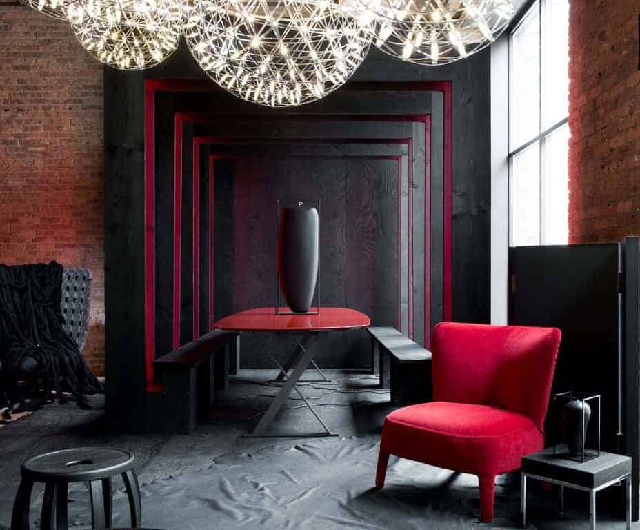 红色天鹅绒椅子和椭圆形餐桌为这个黑色餐厅增添了色彩，展示了圆形集群吊坠和舒适的黑色座椅，与墙壁和地板融为一体。