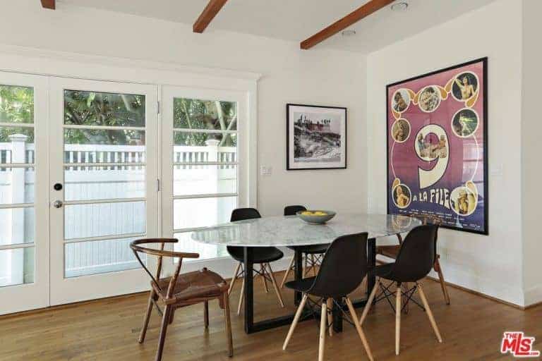 这间餐厅以框架墙艺术和椭圆形大理石桌子为特色，在木质木板地板上配有黑色现代木制圆形靠背椅。