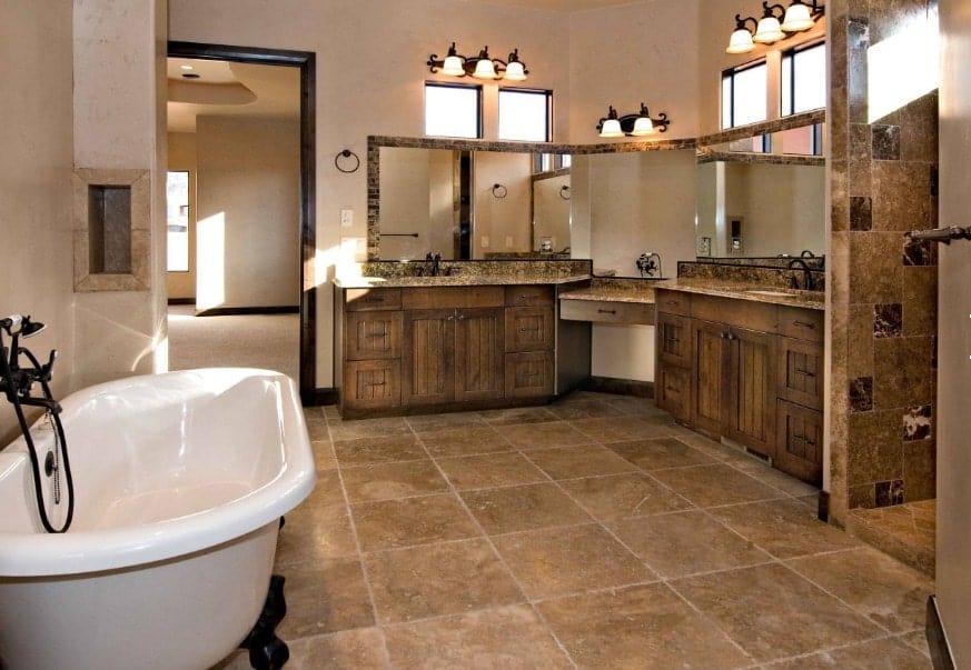 宽敞的主浴室设有质朴的水槽柜台，配有华丽的壁灯，以及独立式浴缸和步入式淋浴房。