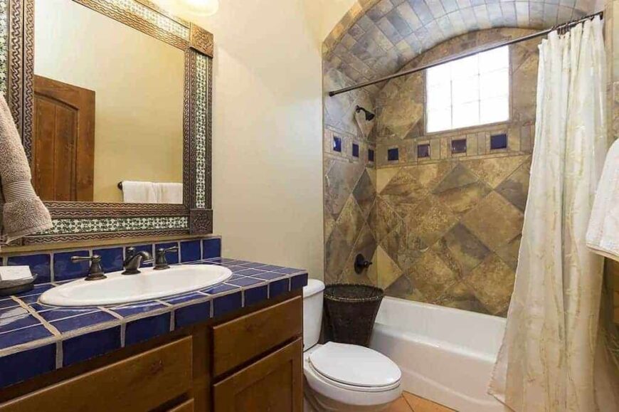 西南风格的主浴室，蓝色瓷砖水槽柜台以及华丽的角落淋浴和浴缸组合设置。