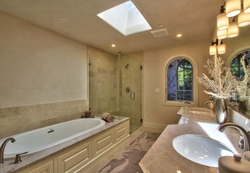 这间主浴室有一扇天窗。它还有一个落地式浴缸、一个步入式淋浴间和一个带两个水槽的单水槽柜台。