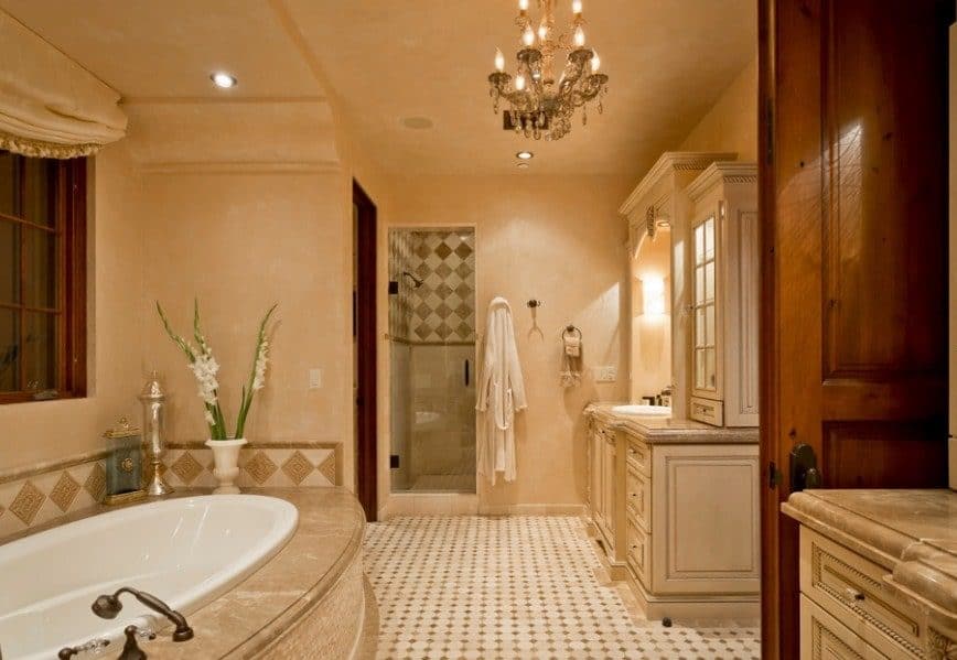 宽敞的西南风格主浴室设有米色墙壁和瓷砖地板。房间里有一盏迷人的枝形吊灯。它提供一个可插入式浴缸和一个步入式淋浴间。