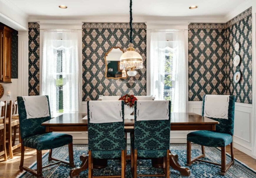维多利亚式的餐厅设计有装饰性的盘子和安装在白色护壁板上的金色镜框镜子。它有一张木制餐桌和绿色图案的椅子，与铺在硬木地板上的区域地毯相辅相成。