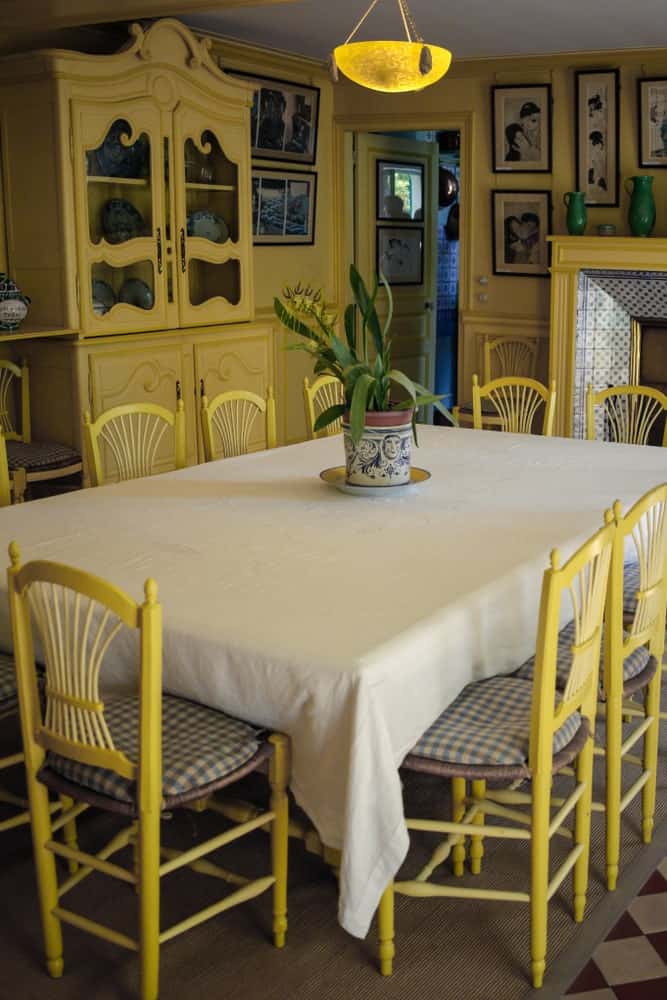 黄色的色调是这个餐厅的主导力量，黄色的乡村椅子，黄色的墙壁与黄色的橱柜融合在一起，黄色的壁炉在长方形餐桌的顶部，上面有桌布。