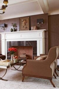 有一个单色配色方案在这优雅的居住空间与棕色丝绒沙发和棕色条纹高背椅扶手椅。棕色画墙壁和窗帘房间添加纹理和华丽的黑色&镶嵌砖壁炉是展示塞在这个精美设计的房间。