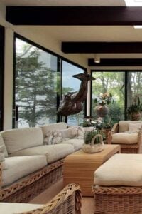 这个宽敞的生活空间的室内外感觉所有的大型落地窗让光和绿色植物。复杂的瓷砖地板添加颜色和兴趣更随意的柳条家具。