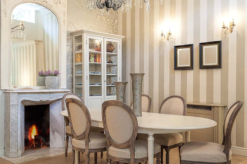 用餐区设有一个优雅的餐桌和椅子，旁边还有一个壁炉。房间被华丽的墙壁包围，并由迷人的吊灯照明。