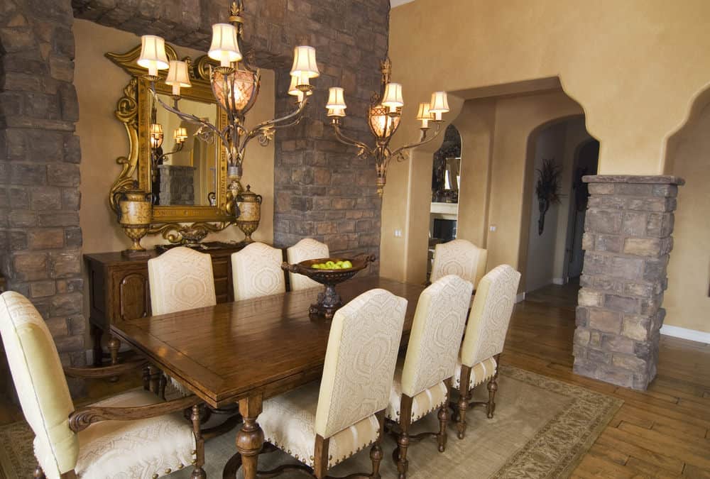 用餐区设有木制餐桌和白色装饰的椅子，放置在覆盖硬木地板的区域地毯上。迷人的枝形吊灯照亮了餐桌。