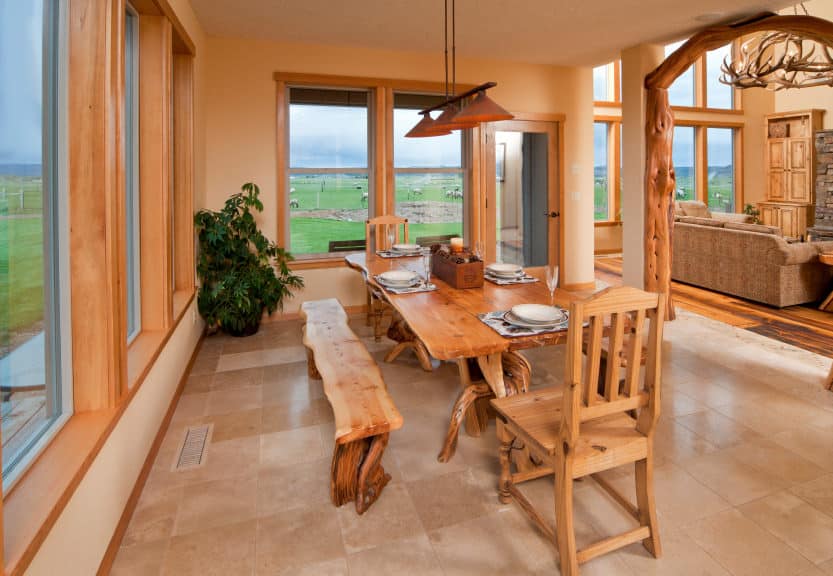 这间餐厅拥有一个木制餐桌和椅子，位于家的大玻璃窗附近。住宅以瓷砖地板和米黄色墙壁为特色。