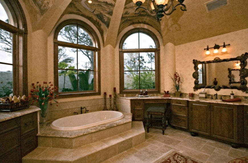 一只绿色软垫凳子放在木制洗手台前，旁边还有一面雕花木镜。这个房间有石灰石地板和拱形窗户，允许自然光线进入。