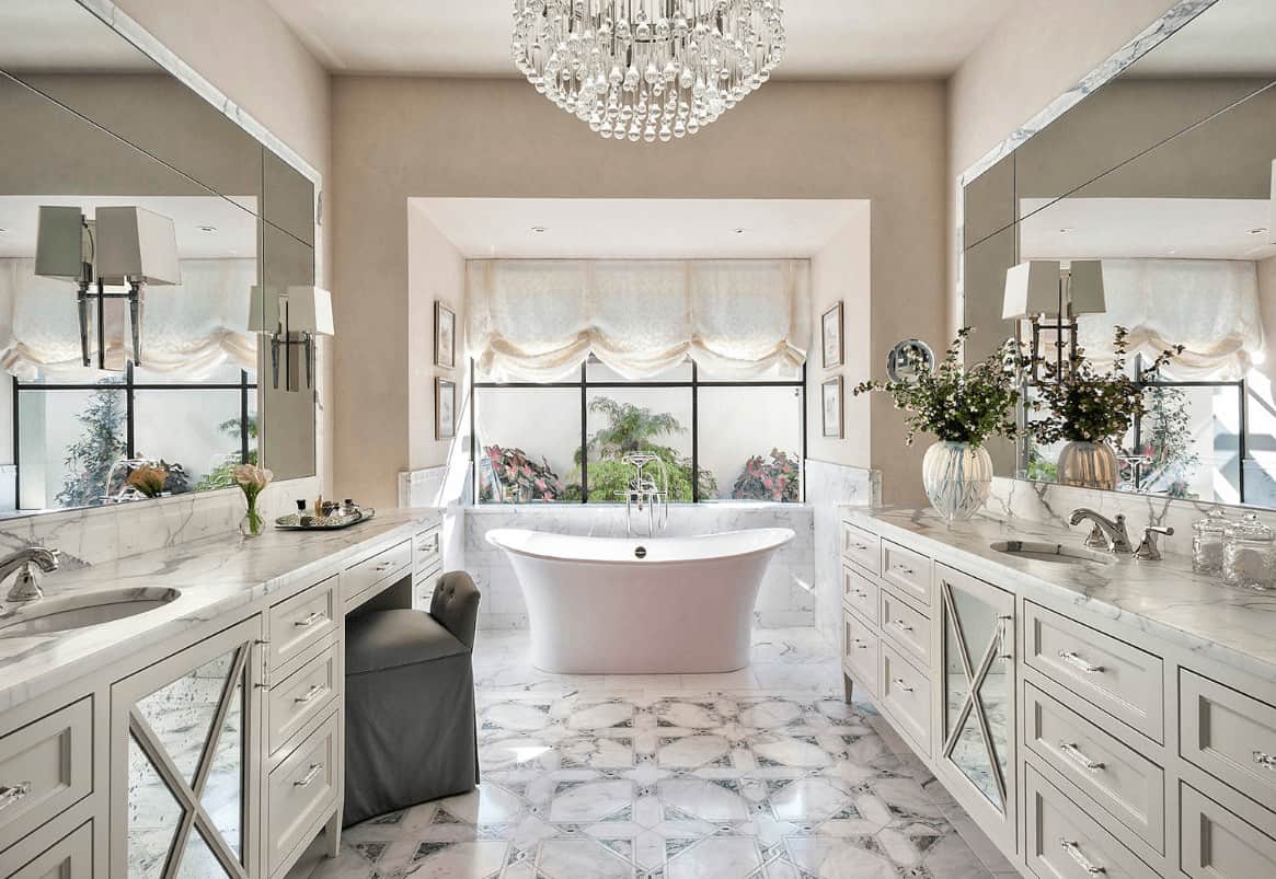 在这个豪华的主浴室里，一盏花式水晶吊灯增加了档次，面朝水槽的梳妆台和一个独立的浴缸，在迷人的罗马阴影中装饰着框窗。