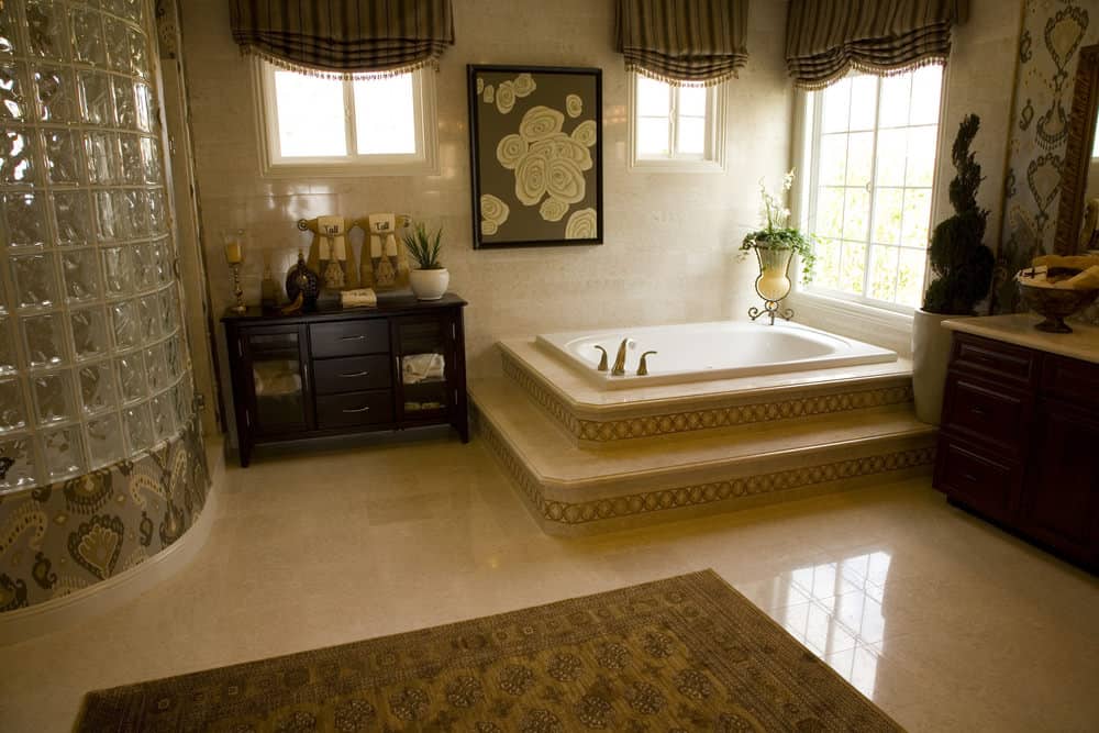 可爱的花墙艺术为这个米黄色的主浴室增添了一个不错的口音，深浸浴缸和步入式淋浴间由纹理玻璃块包围。