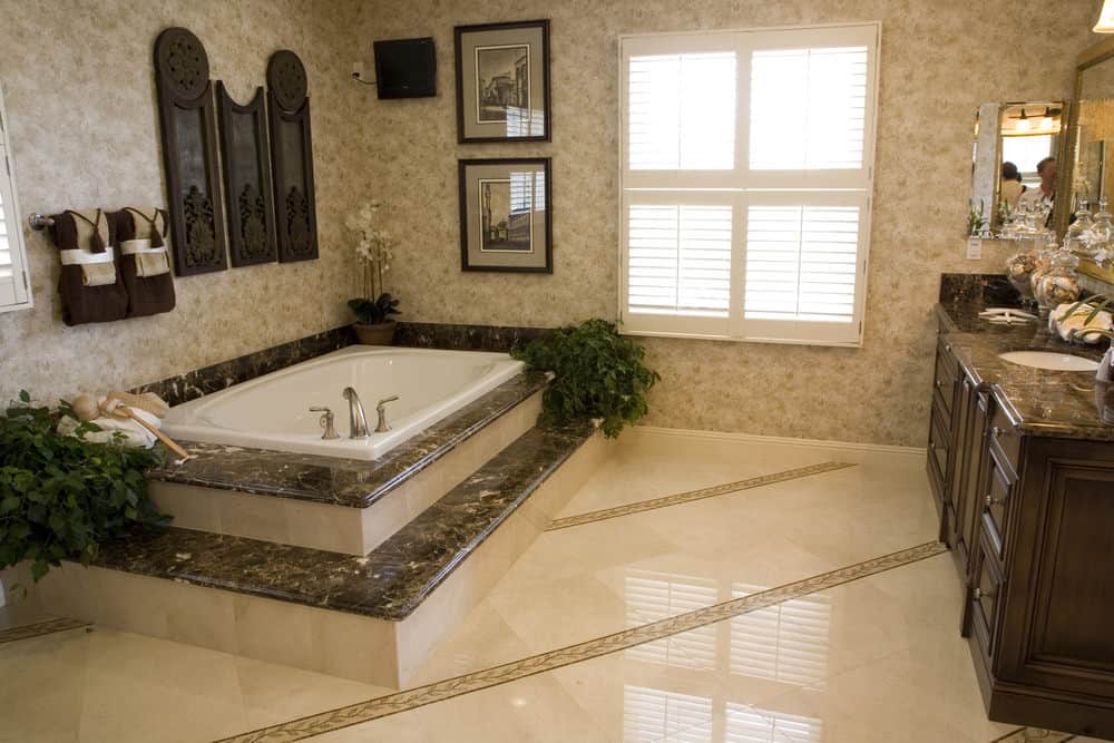 清新的主浴室装饰有框架和深色木墙艺术，安装在深泡浴缸上方。有一个洗手台，上面是黑色大理石台面。