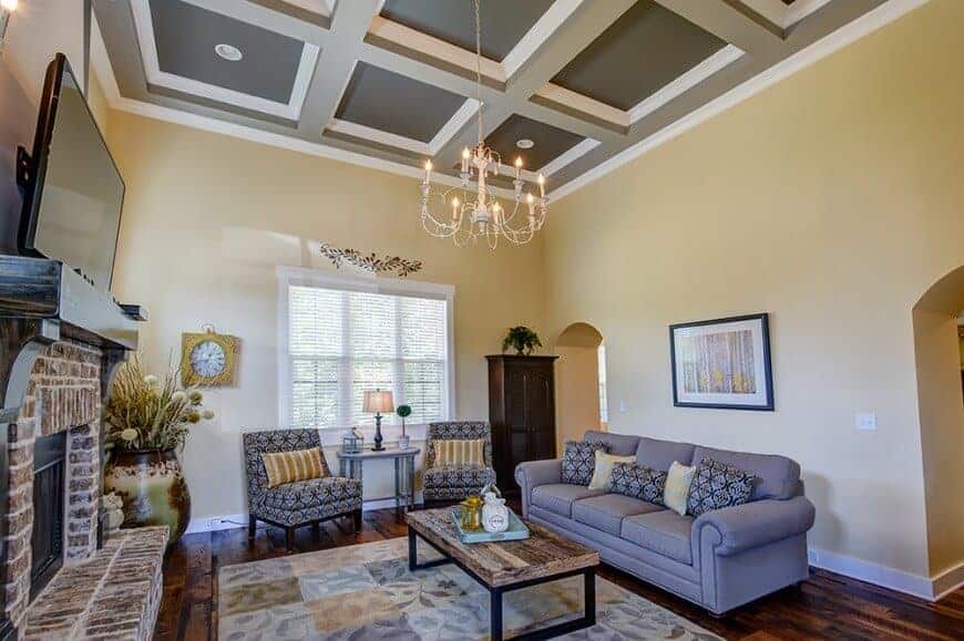 一个优雅的正式客厅设置在华丽的格子天花板下。客房设有一套优雅的沙发和一个大型砖砌壁炉，壁炉顶部有一台宽屏电视。