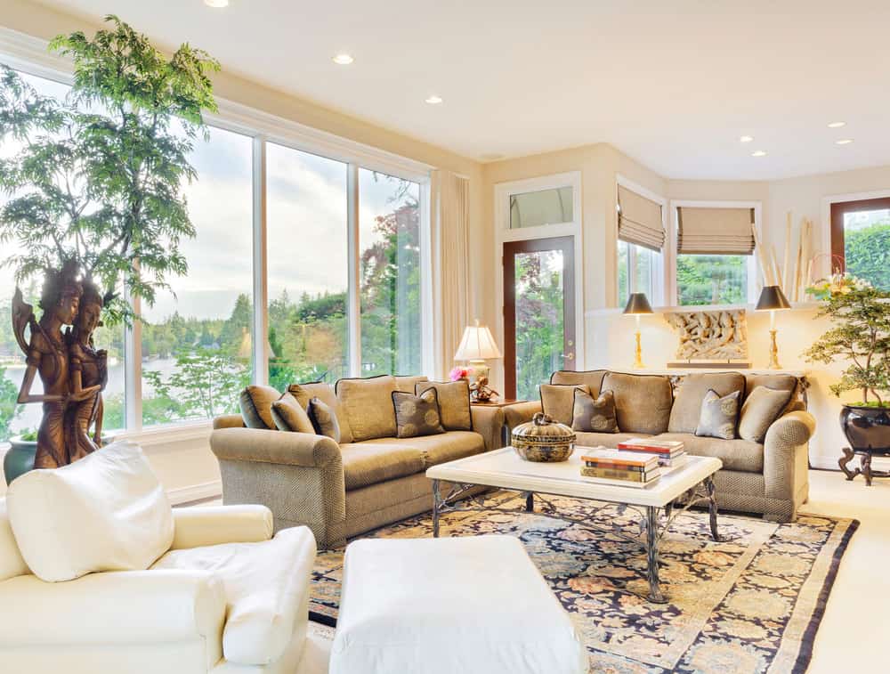 这个乡村风格的客厅提供了一个优雅的沙发套和一个中心桌子位于一个优雅的地毯。房间提供大玻璃窗，俯瞰令人惊叹的环境。该住宅还在该地区种植了室内植物。