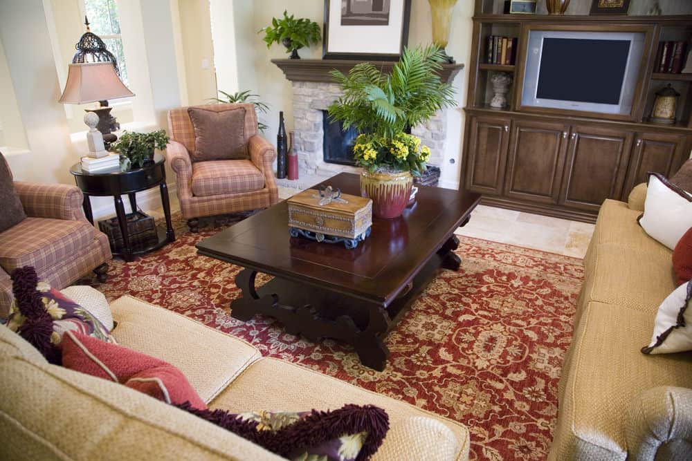一个集中的镜头在这个正式的客厅的高级沙发组和中央桌子位于红色地毯的顶部。该区域有一座壁炉。