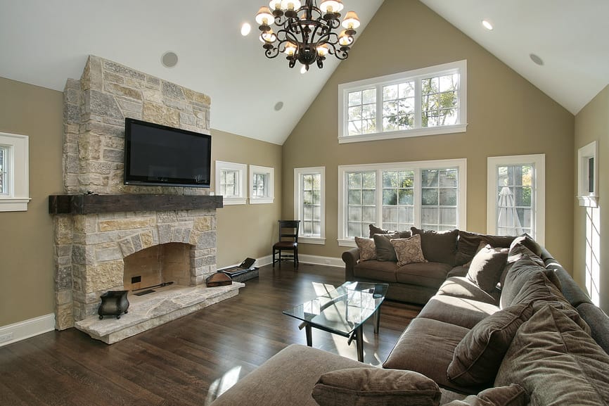 大客厅，有一个棕色的舒适沙发和一个大壁炉，上面有一个大宽屏电视。房间四周是棕色的墙壁和高高的拱形天花板。