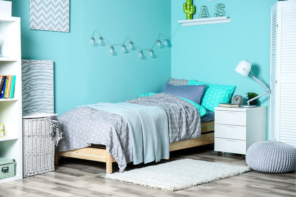 这个孩子卧室的亮绿色墙壁提供了一种轻松而有趣的基调，与灰色元素很好地互动，如波点床单、壁挂式艺术品和白色现代床头抽屉旁的小编织豆袋。