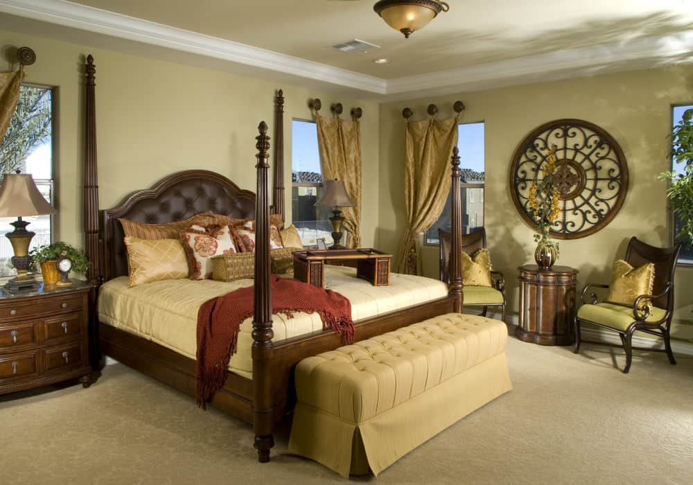 经典的卧室展示了一张四柱床，床的一端是米色的簇绒长椅，一侧的休息区以圆形华丽的墙壁艺术为重点。