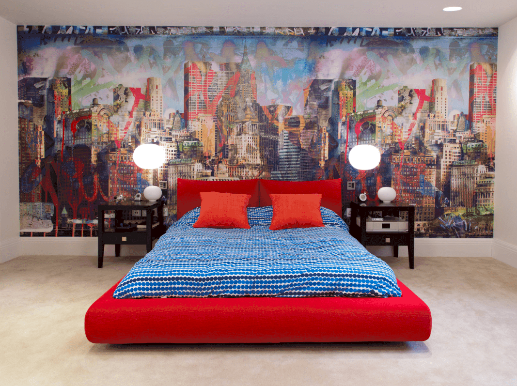 一幅大型壁画是这间时尚卧室的亮点，深色的木质床头柜和一张铺着蓝色圆点床上用品的红色月台床。