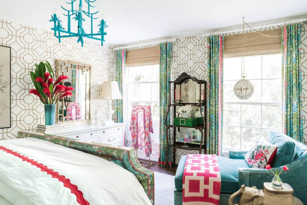 华丽的卧室覆盖着图案墙纸，并配有一面时尚的镜子。它由一个球形吊灯和一个独特的蓝色吊灯照亮，该吊灯悬挂在与窗帘相匹配的绿色印花床上。