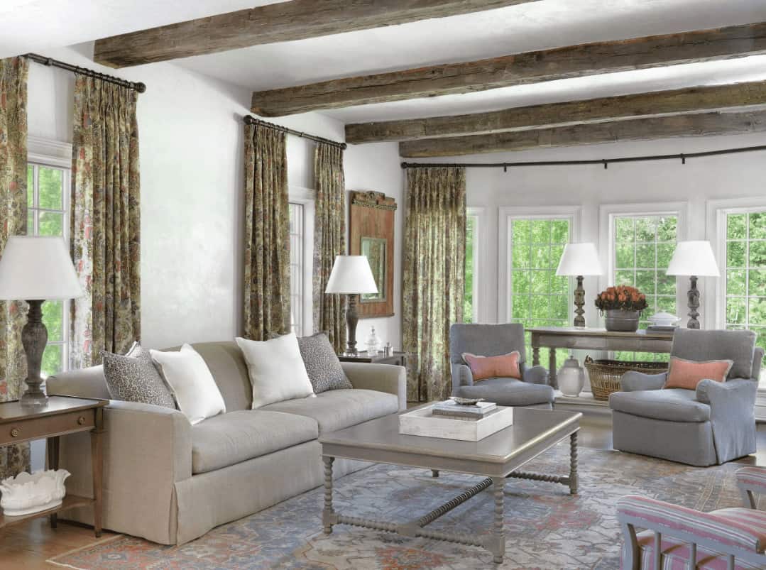 通风的客厅被白色包围框窗口覆盖在花窗帘。它有舒适的座椅和一个灰色的咖啡桌,坐在古董地毯实木地板。