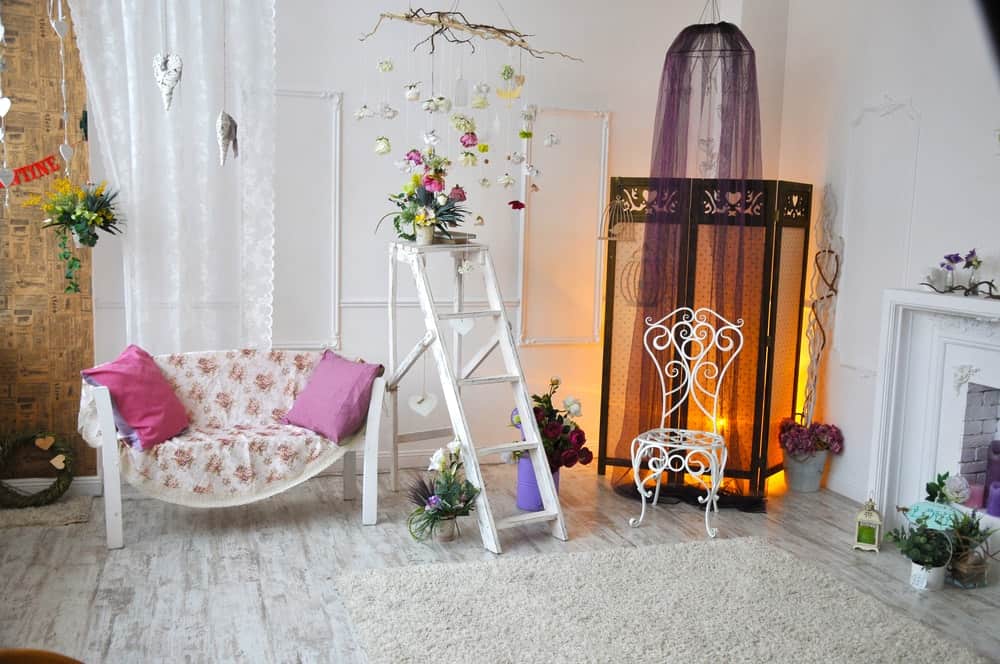 充满魅力的时尚风格的客厅来和三片式屏幕紫色树冠净开销。它包括白色座椅和毛茸茸的地毯在壁炉和硬木地板。