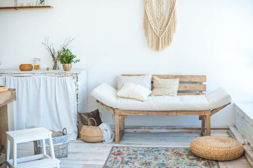 这生活区域展示了一轮柳条奥斯曼和一个木椅上泛起白色垫子和枕头。它包括一个放荡不羁的挂毯和印花地毯,宽板地板了。
