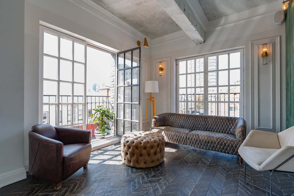 通风的客厅与舒适的座椅和一个圆形的簇绒奥斯曼实木地板安排在雪佛龙模式。窗户和门,打开阳台封装在一个铁艺栅栏。