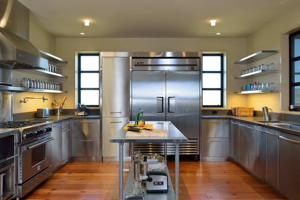 不锈钢橱柜和电器围绕在丰富的硬木地板上的配套厨房岛。它配有嵌入式灯和漂浮的架子，上面摆满了罐子和玻璃器皿。