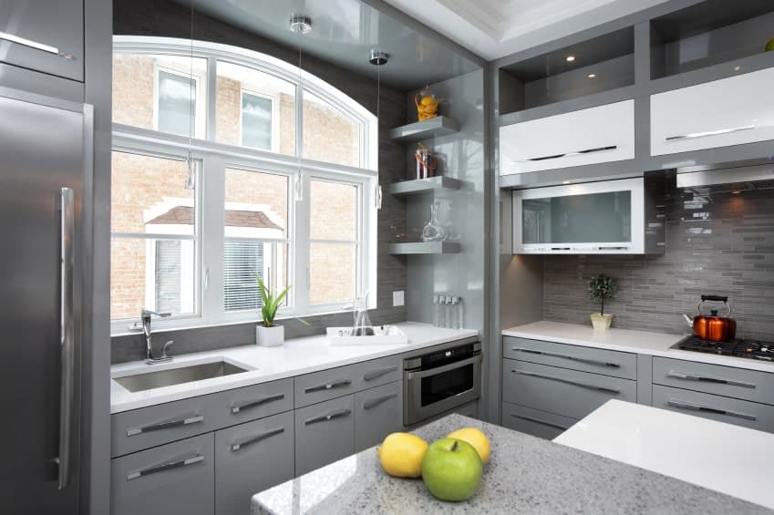 不锈钢电器与这间厨房的灰色橱柜融合在一起，厨房拥有花岗岩和石英台面，以及白色框窗，可以引入自然光线。