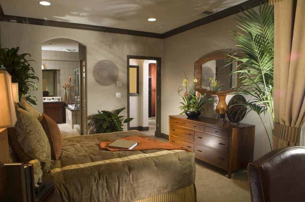 这主卧室里展示了一个可爱的圆墙艺术和有缘的床,面临着抽屉衣柜搭配了一个木制框架镜子。