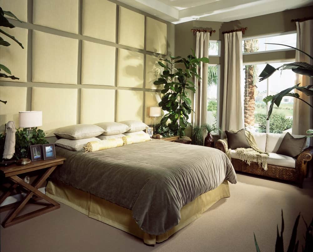 藤沙发泛起白色截面靠垫面临这个主卧室的床有簇绒口音镶窗户的墙和玻璃覆盖着灰色的布料。
