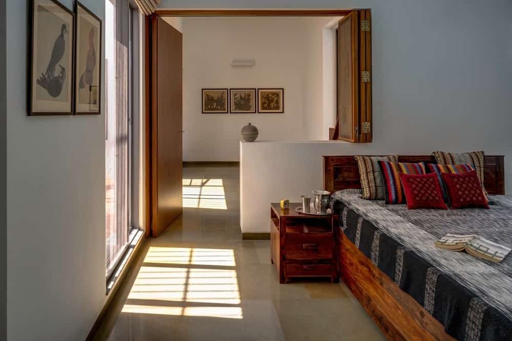 这个迷人的热带风格的卧室里有一个动物主题框架上清楚地看到艺术品,安装在床旁边的白墙。这是与房间的木质元素如平台床,床头抽屉和门。