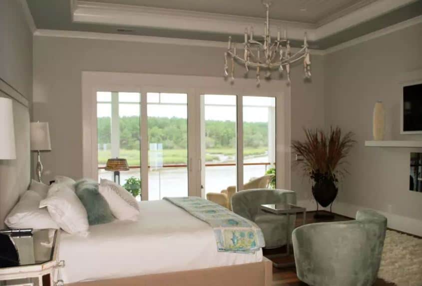 简单的浅灰色和白色的床和墙是辅以绿色天鹅绒坐垫扶手椅的脚床以及绿色枕头和床的围巾。这些绿色的元素是一个漂亮的绿色景观的镜像在玻璃门。