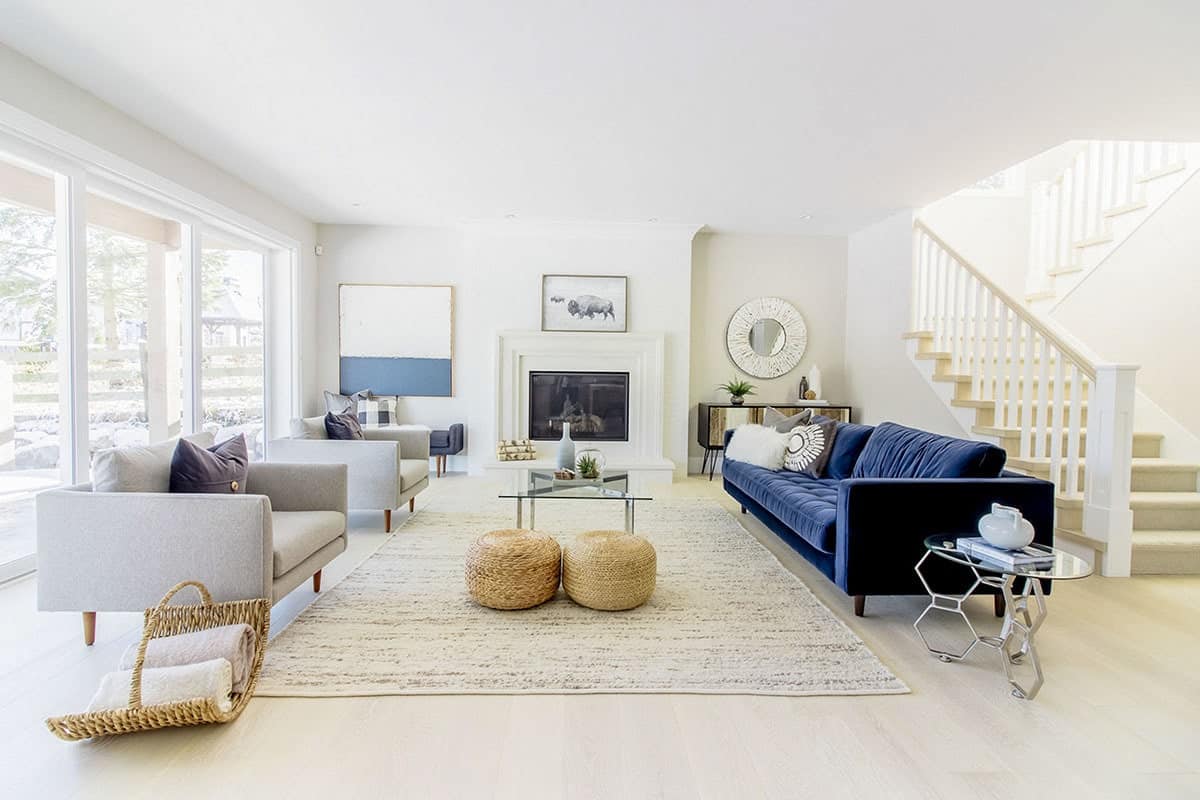 明亮的米黄色天花板和墙壁与浅色硬木地板以及壁炉的覆盖物很好地融合在一起。在这张沙发的对面，深蓝色的沙发在两张浅灰色扶手椅的映衬下显得格外显眼。